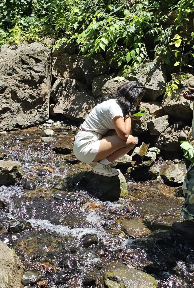 Efratah crouching beside a clear rocky stream in Arba Minch